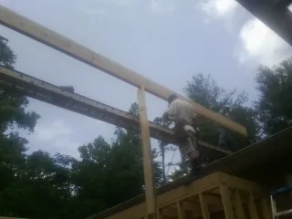 Carpenter setting a ridge beam over a new addition frame — Ice Dam Removal by Roofing Brothers in La Fontaine