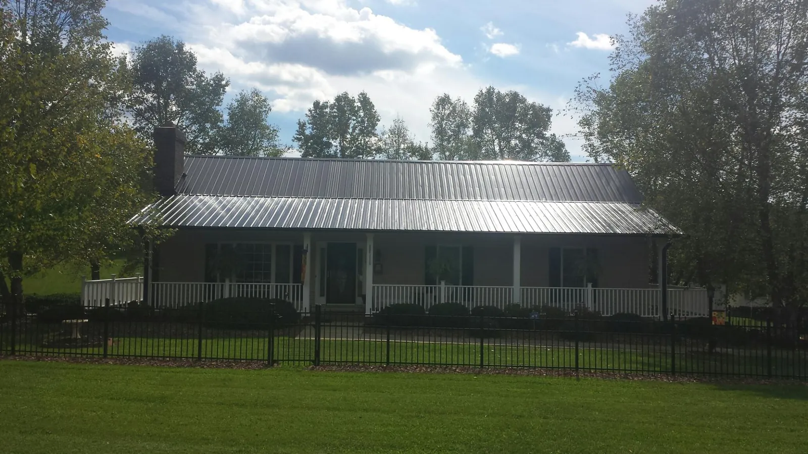 Gray metal roof on a brick ranch with a full width front porch — Gutter Guard Installation work by our crew in La Fontaine