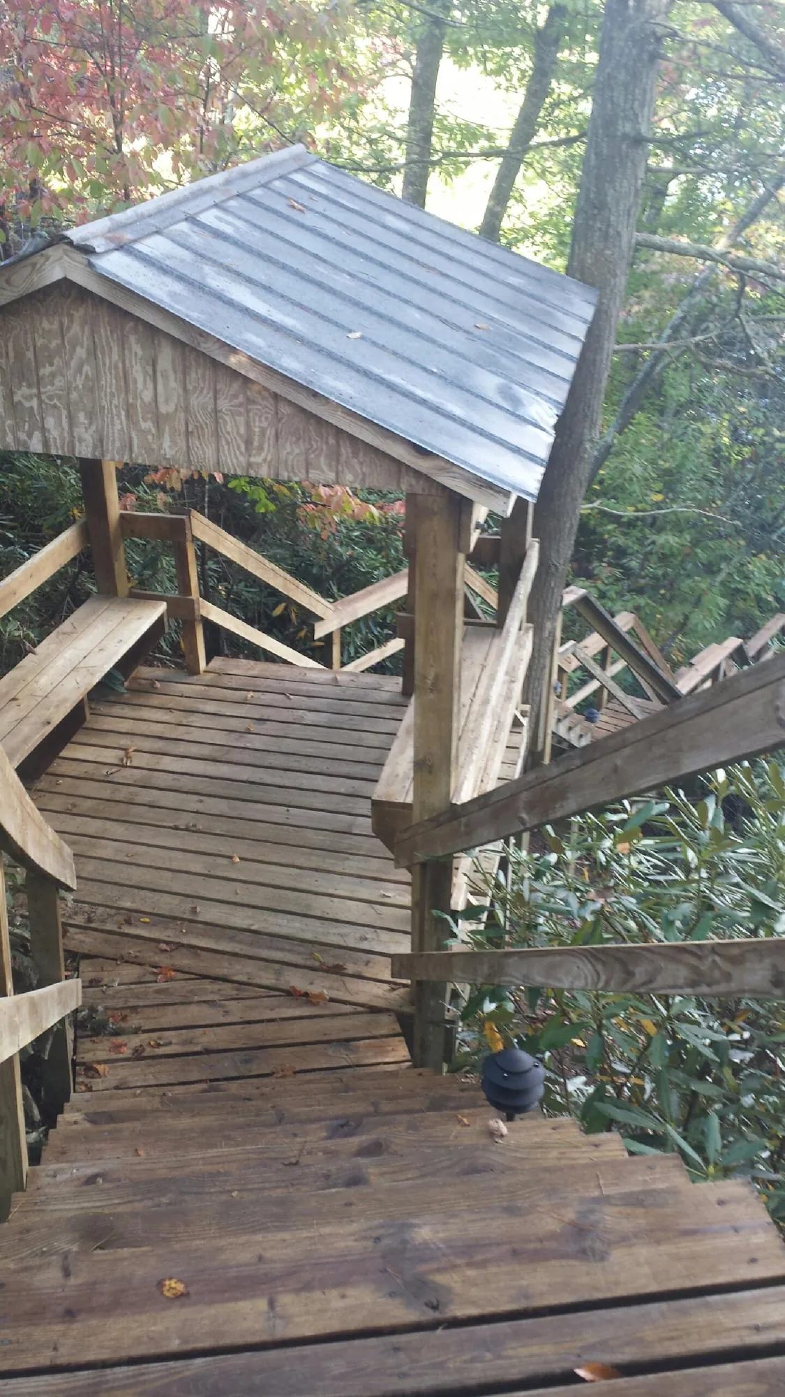 Metal roofed shelter over wooden steps on a wooded walkway — Skylight Repair & Installation work by our crew in La Fontaine