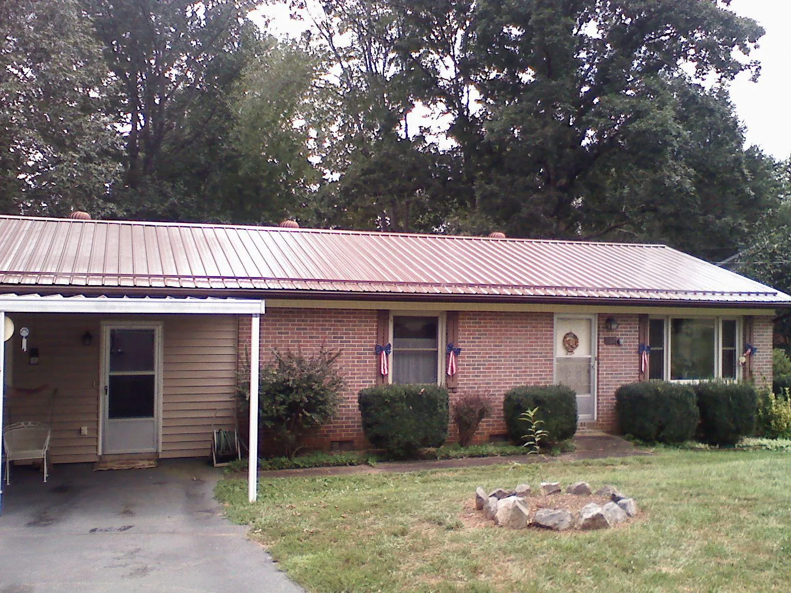 Bronze metal roof and carport on a brick ranch home — Roof Repair work by our crew in La Fontaine